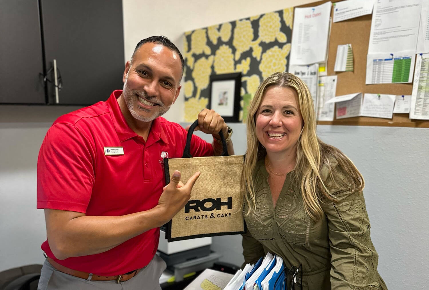ROH Hotel Management Software Onboarding: Doubletree Orlando at SeaWorld Hotel - Image of ROH team member Kasey Denton smiling with a DoubleTree team member and a ROH welcome bag.
